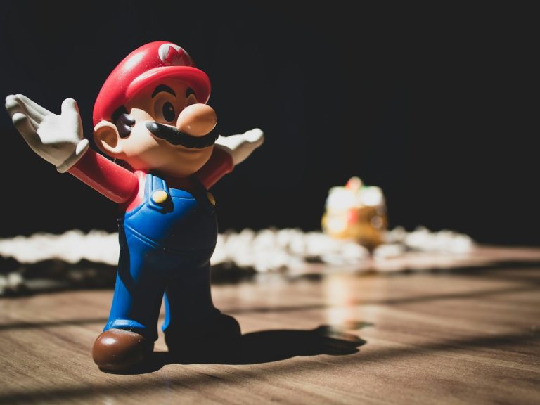 boutique jeux vidéo Figurine de Mario avec les bras ouverts, gâteau en arrière-plan.